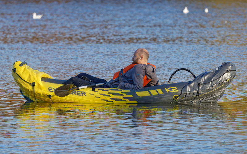 8 - Man relaxing in a yellow and grey Intex Explorer K2 2-Person Inflatable Kayak, a popular model known for its streamlined design and included aluminum oars